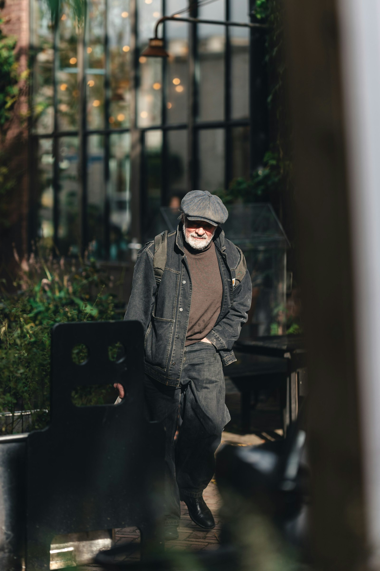 A man in a cap and denim jacket walking